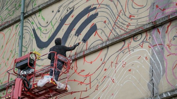 Der Hamburger Urban Art-Künstler 1010 arbeitet auf einem Hubsteiger an einem riesigen Wandbild am Hochbunker im Stadtteil Altona. © picture alliance / dpa Foto: Axel Heimken