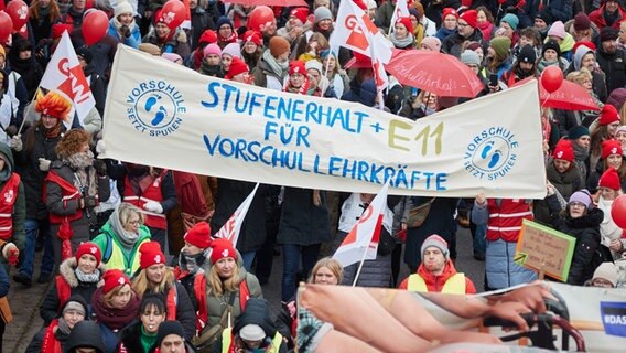 Demonstrierende halten bei einer Kundgebung auf dem Dammtordamm ein Transparent mit der Aufschrift "Stufenerhalt für Vorschullehrkräfte + E11" © Georg Wendt/dpa Foto: Georg Wendt