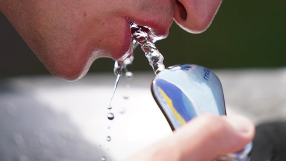 Ein Mann in Hamburg trinkt Wasser aus einem Wasserspender. © picture alliance / dpa 