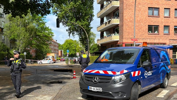 Mehrere Einsatzkräfte der Polizei stehen aufgrund eines Wasserrohrbruchs vor einem Gebäude. © HamburgNews 