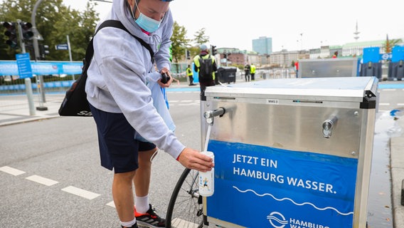 Ein Mann nimmt Wasser von einem Wasserspender beim Triathlon in Hamburg © Hamburg Wasser Foto: Hamburg Wasser