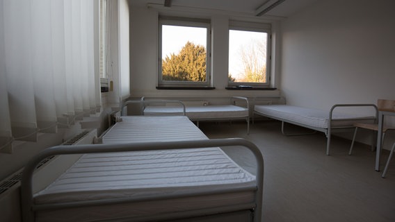 Betten stehen in einer behelfsmäßigen Unterkunft. © dpa Foto: Christian Charisius