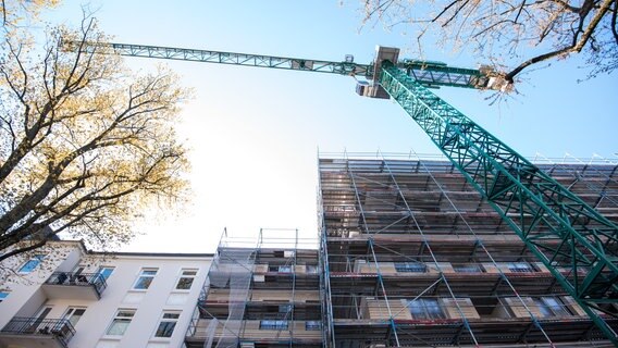 Ein Baukran steht vor einem im Bau befindlichen Gebäude. © dpa Foto: Daniel Bockwoldt