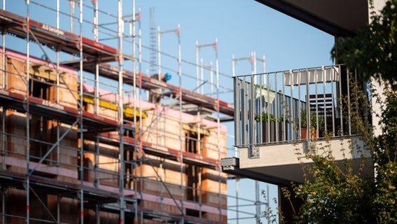 Ein Gerüst steht an der Baustelle eines Neubaus in Stuttgart. Neben der Baustelle steht ein bereits fertig gestellter Neubau © dpa Foto: Sebastian Gollnow