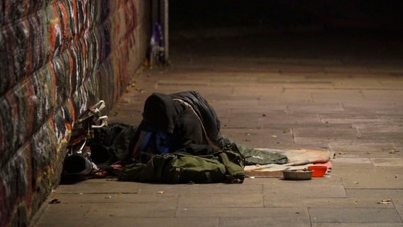 Ein Obdachloser liegt mit seinen Habseligkeiten auf dem Gehweg bei Minusgraden. © picture alliance 