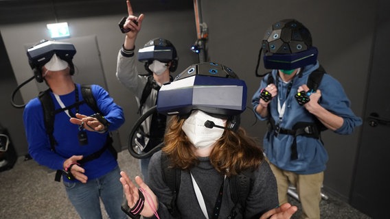 Menschen mit Rucksack und Helm sowie Hand- und Fußsensoren und Tracker in der neuen Virtual-Reality-Attraktion "Yullbe" im Miniatur Wunderland in Hamburg. © picture alliance / dpa Foto: Marcus Brandt