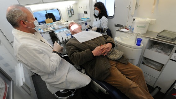 Ein Zahnarzt und die Zahnarzthelferin behandeln einen Patienten in einem Zahnmobil in Hamburg. © dpa Foto: Marcus Brandt