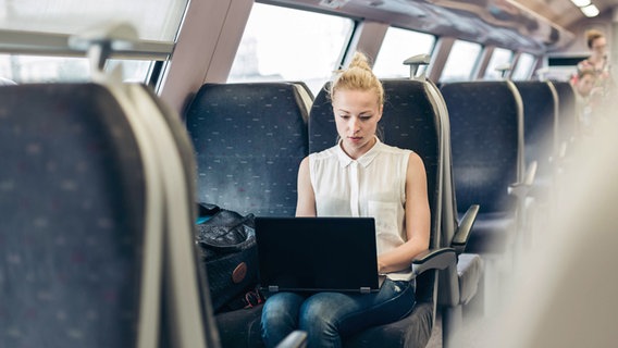 Eine junge Frau nutzt einen Laptop auf einer Zugfahrt. © xZoonar.com/MatejxKastelicx 20855948 