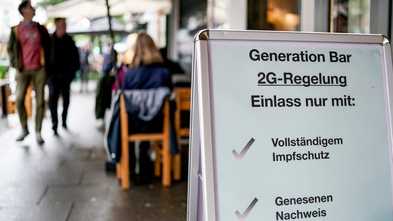 Vor einer Bar im Hamburger Stadtteil St. Georg steht ein Hinweisschild, welches auf den Einlass nach der 2G-Regel hinweist. © picture alliance/dpa Foto: Axel Heimken