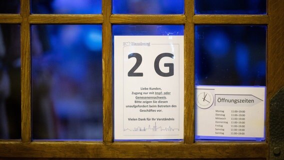 Ein Hinweisschild zu den 2G-Maßnahmen hängt an der Eingangstür eines Geschäfts in Hamburg. © picture alliance/dpa Foto: Daniel Reinhardt