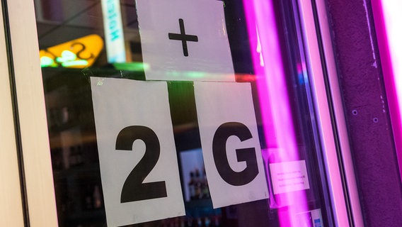 Schilder, die auf "2G-Plus" hinweisen, hängen an einem Tanzlokal. © picture alliance/dpa Foto: Daniel Bockwoldt