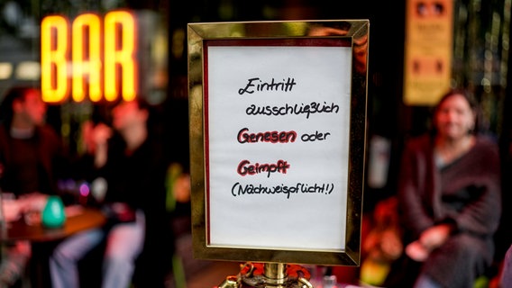 Vor einer Bar steht ein Schild mit einem Hinweis auf die 2G-Regel. © dpa Foto: Axel Heimken
