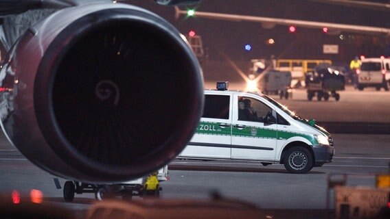 Ein Polizeifahrzeug steht hinter einem Flugzeug  