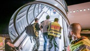 Polizeibeamte begleiten einen Mann, der abgeschoben werden soll, auf dem Flughafen Leipzig-Halle in ein Charterflugzeug. © dpa Foto: Michael Kappeler