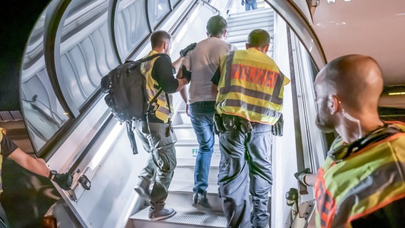 Polizeibeamte begleiten einen Afghanen auf dem Flughafen Leipzig-Halle in ein Charterflugzeug. © dpa bildfunk Foto: Michael Kappeler