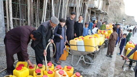 Männer füllen Wasser auf einer Straße in Kabul in Behälter. © picture alliance 