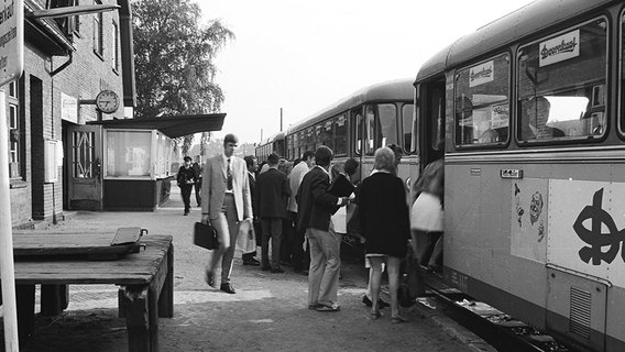 Menschen steigen am Bahnhof in Quickborn in einen Zug ein. Das Foto ist schwarz-weiß und wurde ca. Mitte des 20. Jahrhunderts aufgenommen. © AKN Eisenbahn AG 