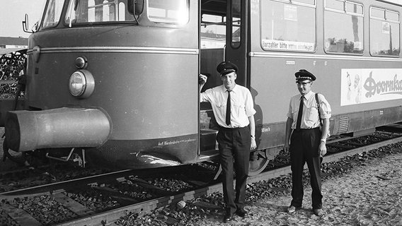 Zwei Lokführer stehen neben einem Zug der AKN. Das Foto ist schwarz-weiß und wurde ca. Mitte des 20. Jahrhunderts aufgenommen. © AKN Eisenbahn AG 