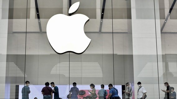 Das Bild zeigt das Logo von Apple und mehrere Menschen in einem Apple-Store. © dpa bildfunk/ZUMA Press Wire Foto: Liau Chung-Ren