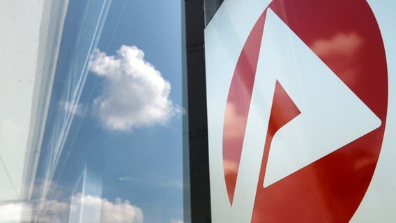 Logo der Bundesagentur für Arbeit vor einem Fenster, in dem sich der Himmel spiegelt. © picture alliance Foto: Jens Kalaene