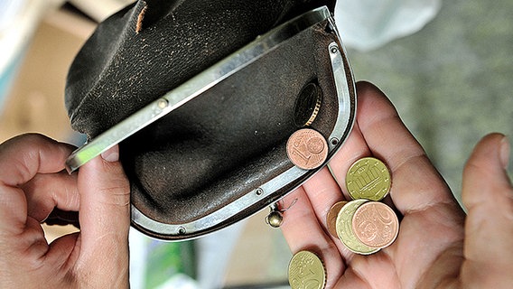 Eine Frau nimmt ein paar Münzen aus einer zerrissenen Geldbörse in die Hand. © picture-alliance/ ZB Foto: Hans Wiedl