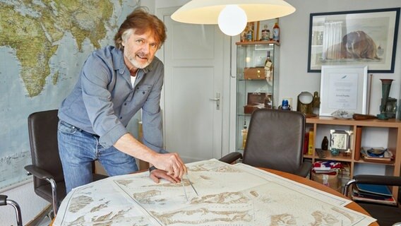 Arved Fuchs steht in seinem Haus in Bad Bramstedt vor ausgebreiteten Seekarten. © dpa Foto: Georg Wendt