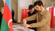Zwei Männer geben ihre Stimmen bei der vorgezogenen Präsidentenwahl in der aserbaidschanischen Hauptstadt ab. © Hannah Wagner/dpa 