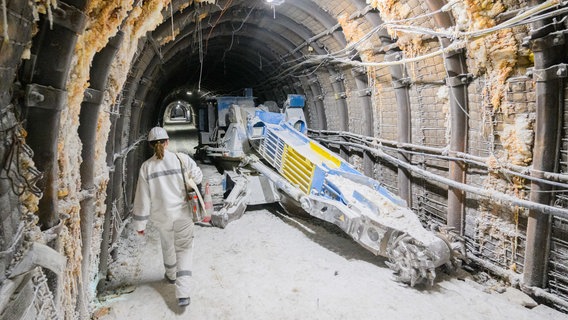 Mitarbeiterin geht in einem Schacht im Atommülllager Asse an einer Fräs-Maschine entlang. © Julian Stratenschulte/dpa Foto: Julian Stratenschulte/dpa