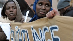 Asylbewerberinnen halten ein Plakat mit der Aufschrift "Flüchtlinge" in der Hand. © dpa - Bildfunk Foto: Stefan Puchner