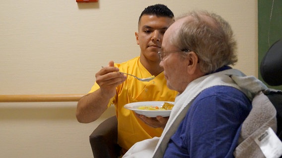 Mohammad Berri füttert einen Senioren. © NDR Foto: Kai Salander