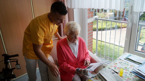 Mohammad Berri spricht mit einer Seniorin, die auf eine Zeitschrift deutet. © NDR Foto: Kai Salander