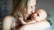 Eine Mutter hält ihr Baby im Arm und küsst es. © picture alliance / Westend61 Foto: Nina Janeckova