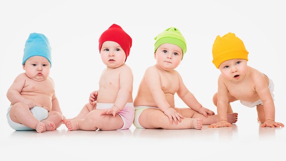 Vier Babys mit unterschiedlich farbigen Mützen posieren fürs Foto. © Fotolia.com Foto: Svetlana Fedoseeva