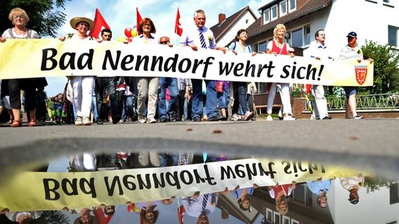 Menschen tragen ein Banner mit der Aufschrift: "Bad Nenndorf wehrt sich" © dpa Foto: dpa