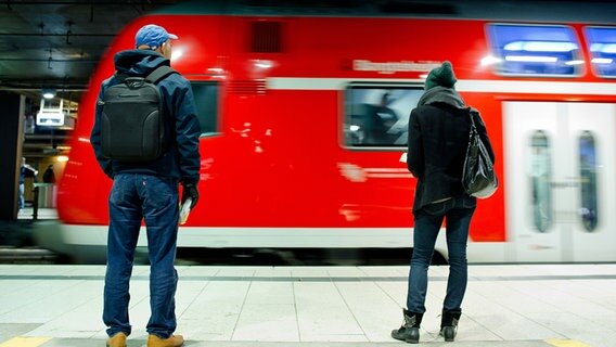 Eine Regionalbahn fährt in Hamburg in den Hauptbahnhof ein. Zwei Reisende stehen am Bahnsteig. © picture alliance / dpa Foto: Daniel Bockwoldt