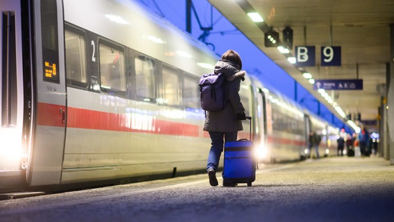 Eine Frau geht mit einem Koffer neben einem ICE im Hauptbahnhof Hannover. © dpa Foto: Julian Stratenschulte