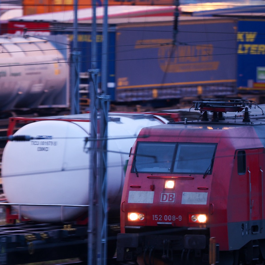 Eine E-Lok fährt zwischen Güterzugwaggons durch einen Umschlagbahnhof © picture alliance/dpa Foto: Jan Woitas