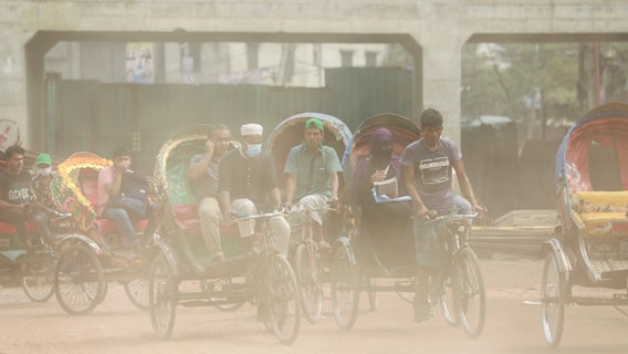 Dichter Staub liegt über einer Straßenszene in Dhaka. Die Menschen in Bangladeschs Hauptstadt leiden unter enormer Luftverschmutzung. In der Zeit der Monsunregenfälle stehen mitunter große Teile der Stadt unter Wasser. (Foto vom 16.10.2023) © picture alliance / abaca | Suvra Kanti Das/ABACA 