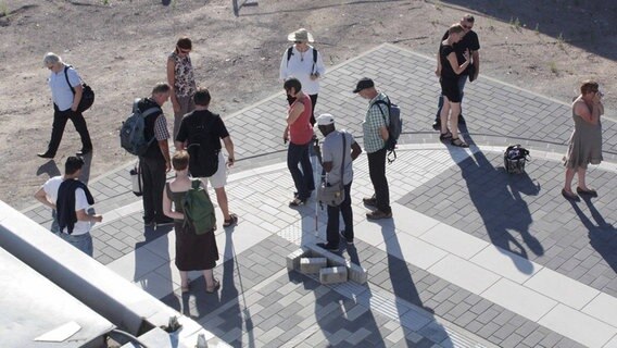 Mehrere Menschen begutachten einen gepflasterten Platz. Einer der Menschen hält einen Blindenstock in der Hand. © Projektleitung Q8 Altona Foto: Projektleitung Q8 Altona
