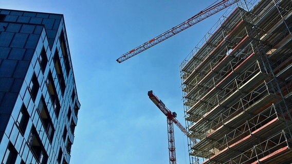 Auf einer Baustelle ist der Rohbau von zwei mehrstöckigen Häusern sowie ein Kran zu sehen. © ARD Foto: Karl Dietrich Mäurer