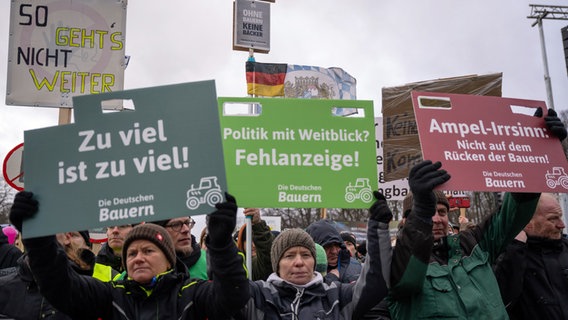 Bei einer Großkundgebung in Berlin halten einige Landwirte Protest-Schilder hoch. © dpa Foto: Monika Skolimowska