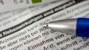 Ein Kugelschreiber liegt auf einem Beipackzettel mit Text über Nebenwirkungen bei einem Medikament. © picture alliance / Zoonar | stockfotos-mg 
