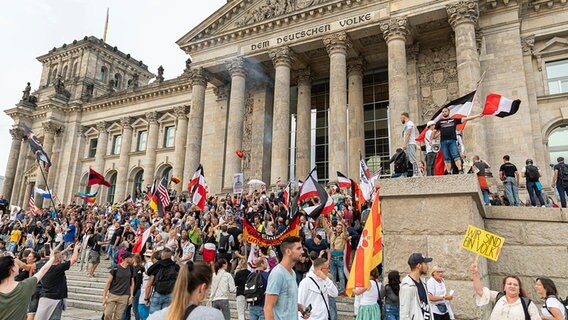 Teilnehmer einer Kundgebung gegen die Corona-Maßnahmen stehen auf den Stufen zum Reichstagsgebäude in Berlin, zahlreiche Reichsflaggen sind zu sehen. © dpa bildfunk/NurPhoto Foto: Achille Abboud