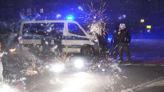 Berliner Polizeibeamte stehen im Jahr 2022 hinter explodierendem Feuerwerk. © TNN/dpa Foto: Julius-Christian Schreiner