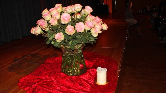 Ein Strauß Rosen und eine Kerze stehen auf einer Bühne © NDR.de Foto: Kristina Festring-Hashem Zadeh