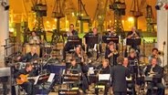 Die NDR Bigband im Studio vor einer Kulisse aus Kränen im Hamburger Hafen. © NDR 