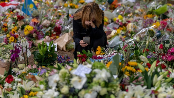 Großbritannien, London: Eine Frau kniet im Green Park Memorial neben dem Buckingham Palace inmitten von Blumen, die anlässlich des Todes von Königin Elizabeth II. niedergelegt worden sind. © AP/dpa Foto: Emilio Morenatti