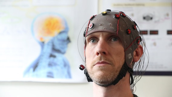 Ein Mann mit einer EEG Haube © picture alliance 