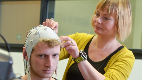 Forscherin Andrea Finke von der Universität Bielefeld legt eine EEG Haube an.  