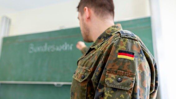 Ein Bundeswehrsoldat von der Seite vor einer Tafel, auf der Bundeswehr zu lesen ist. © Filmbildfabrik/Shotshop/picture alliance 